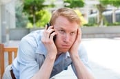 Man exasperated after being on hold for a long period of time. Photo by Shutterstock